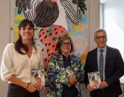 Trois personnes tiennent des affiches.